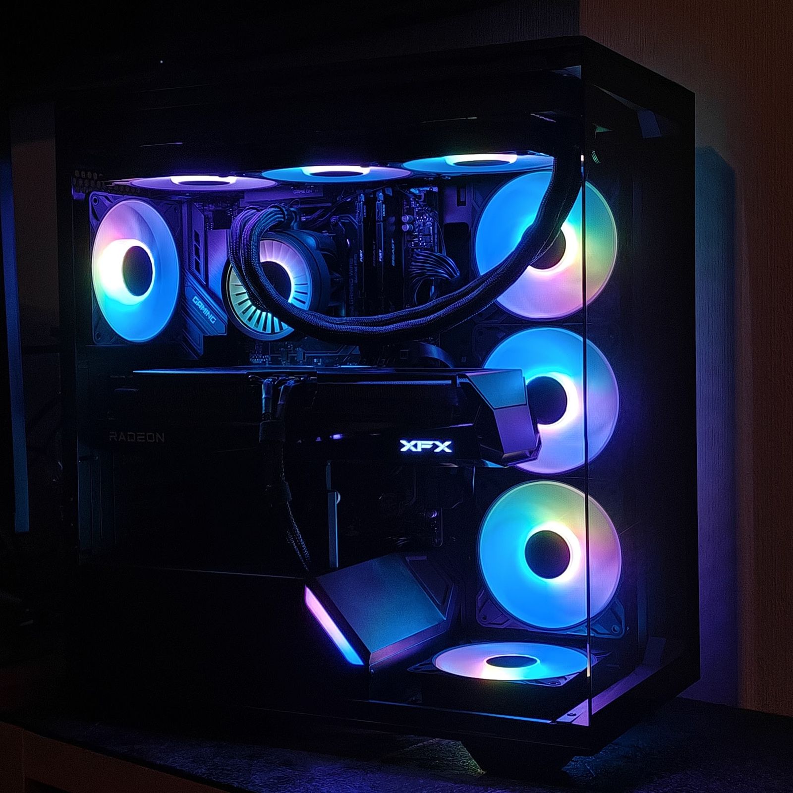 Zwarte pc met zeven RGB-fans in blauw, paars en roze en een XFX Radeon-videokaart, in een donkere kamer