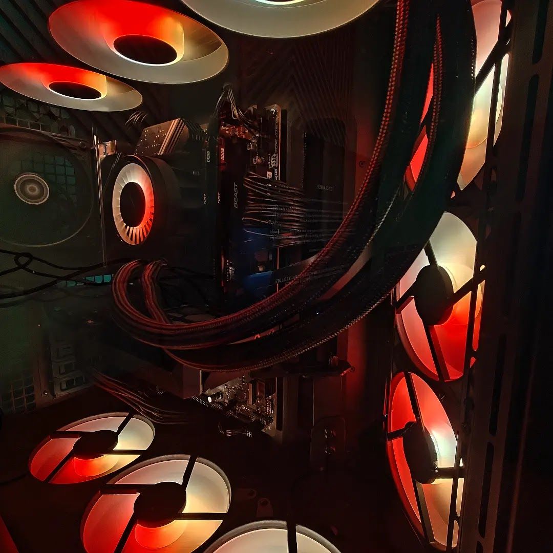 Binnenkant van een pc met zwarte gesleevde kabels en fans die rood en oranje oplichten